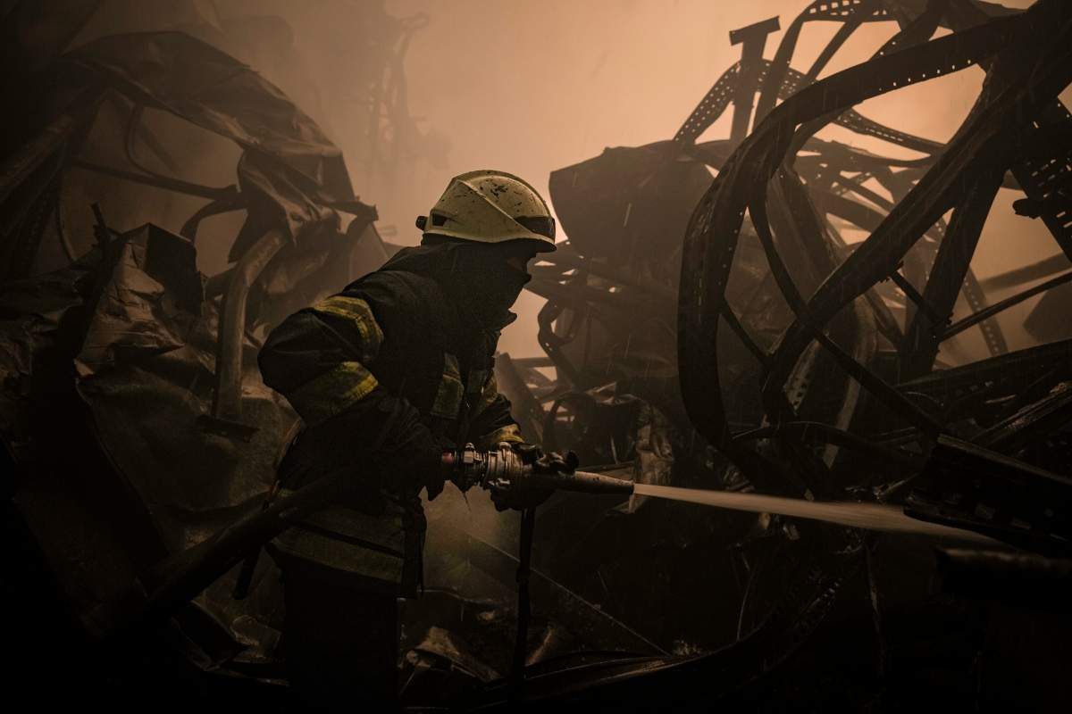 A Ukrainian firefighter extinguishes fire inside a large food products storage facility which was destroyed by an airstrike in the early morning hours on the outskirts of Kyiv, Ukraine, Sunday, March 13, 2022.