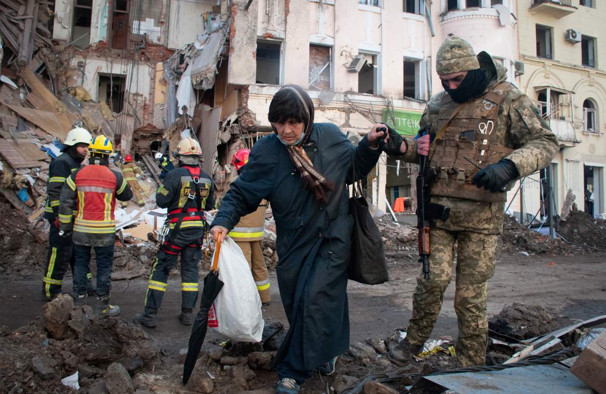 A volunteer of the Ukrainian Territorial Defense Forces assists a woman to cross the street in Kharkiv, Ukraine, Wednesday, March 16, 2022.
