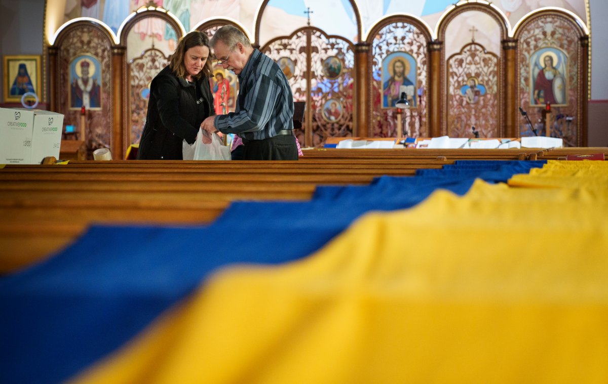 A volunteer sorts through donations destined to Ukraine with a large Ukrainian flag draped over the pews at the St. Michael's Ukrainian Catholic Church in Montreal on Friday, March 25, 2022. Most goods are destined for overseas while others are needed for refugees arriving in Montreal. 