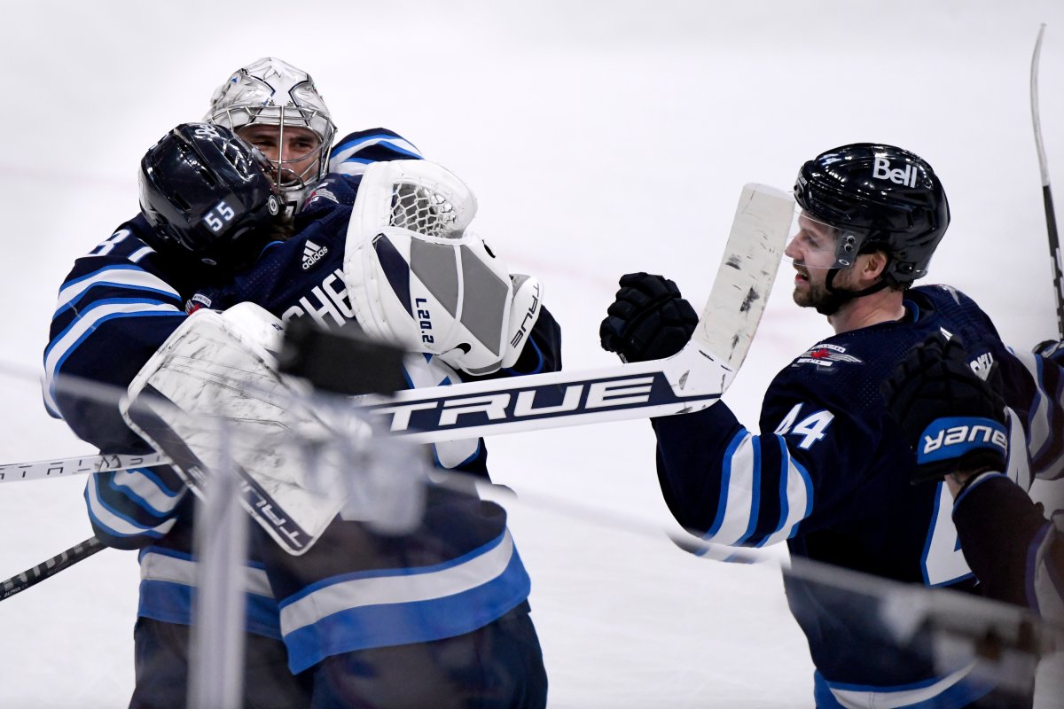 Winnipeg Jets' Mark Scheifele (55) celebrates his game-winning goal in overtime against the Arizona Coyotes with goaltender Connor Hellebuyck (37) and Josh Morrissey (44) during NHL action in Winnipeg on Sunday March 27, 2022.