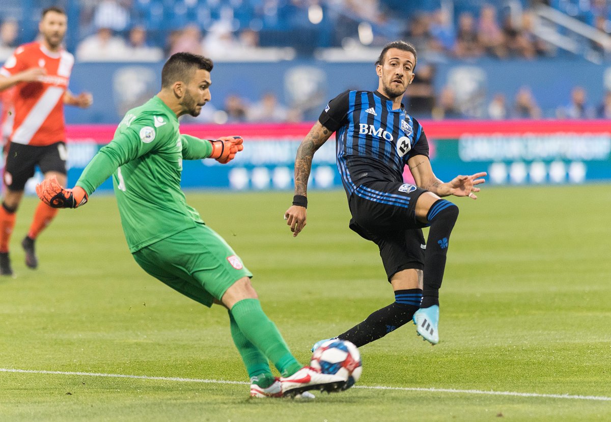 Montreal Impact's Maximiliano Urruti moves in on Cavalry FC goalkeeper Marco Carducci during first half semi-final Canadian championship soccer action in Montreal, Wednesday, August 7, 2019.