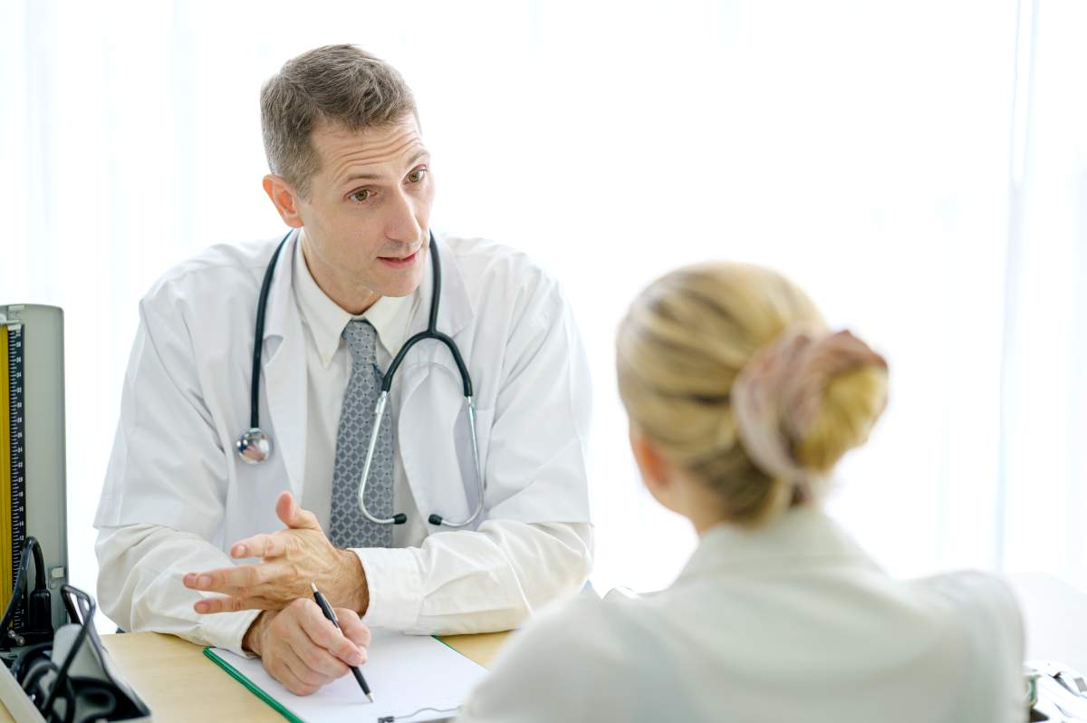 Senior doctor wearing a uniform consultation and talking to a young woman patient in the medical clinic. Medicine and health care concept.