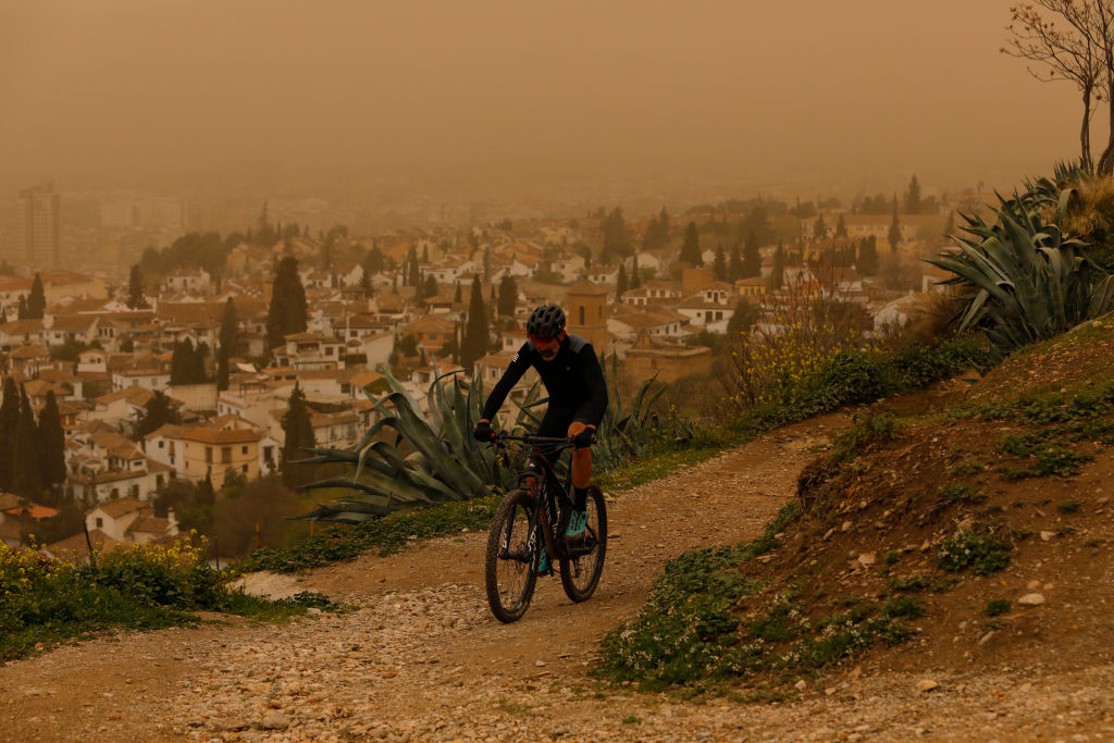 A man rides his bike as a Saharan dust haze covers Granada