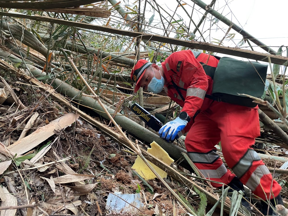 Photo taken with a mobile phone shows a rescuer searching for the black boxes at a plane crash site in Tengxian County, south China’s Guangxi Zhuang Autonomous Region, March 22, 2022. Rescuers are making all-out efforts to retrieve the black boxes of a passenger plane that crashed in south China’s Guangxi Zhuang Autonomous Region Monday afternoon, an official with the Civil Aviation Administration of China CAAC said Tuesday night. The passenger plane with 132 people aboard crashed on Monday afternoon, the regional emergency management department said. The China Eastern Airlines Boeing 737 aircraft, which departed from Kunming and was bound for Guangzhou, crashed into a mountainous area near the Molang village in Tengxian County in the city of Wuzhou at 2:38 p.m., causing a mountain fire, according to the department. The airline said the cause of the accident will be fully investigated.