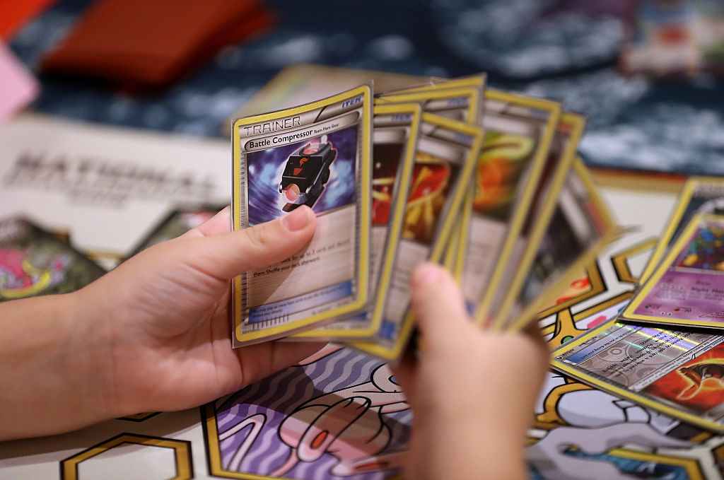 a close up of hands holding a half dozen pokemon cards