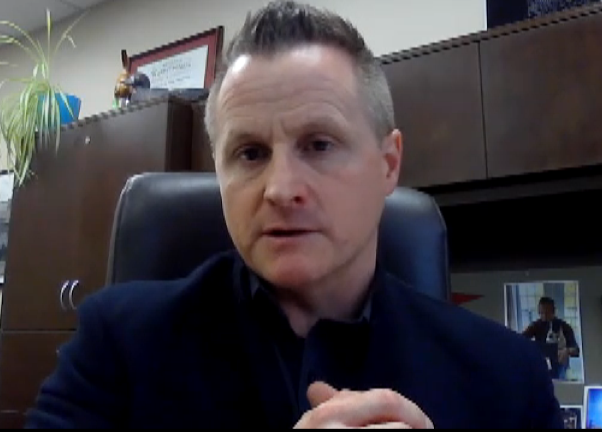 Town of Sackville CAO sits at his desk wearing a navy blue suit jacket.