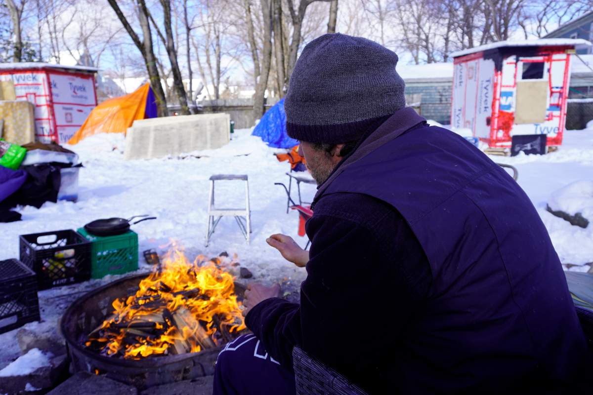 A resident of People’s Park encampment in Halifax warms his hands over a fire, Mar. 4, 2022.