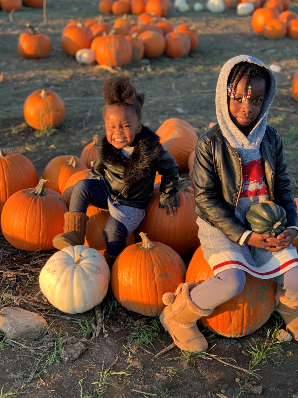 Two of Regina Magambo's three children, Selena and Olympia, sitting on pumpkins