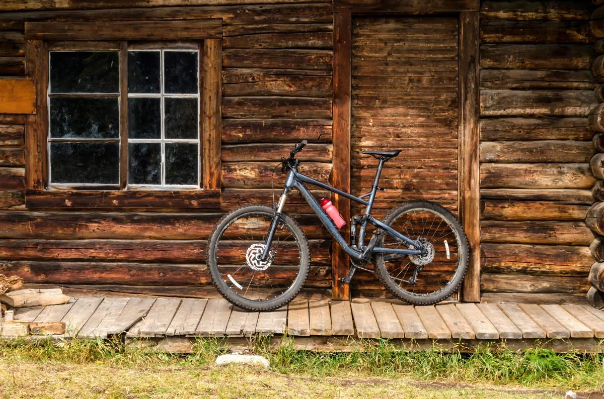A bike in front of a log cabin door.