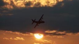 A Canadian Forces transport aircraft flies in front of a cloud silhouetted by a setting sun.