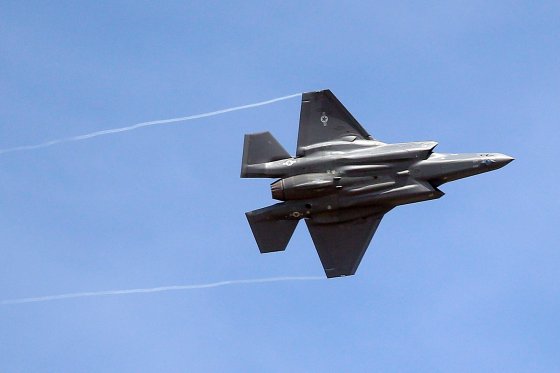 A Lockheed Martin F-35 fighter jet flies against a cloudless blue sky.