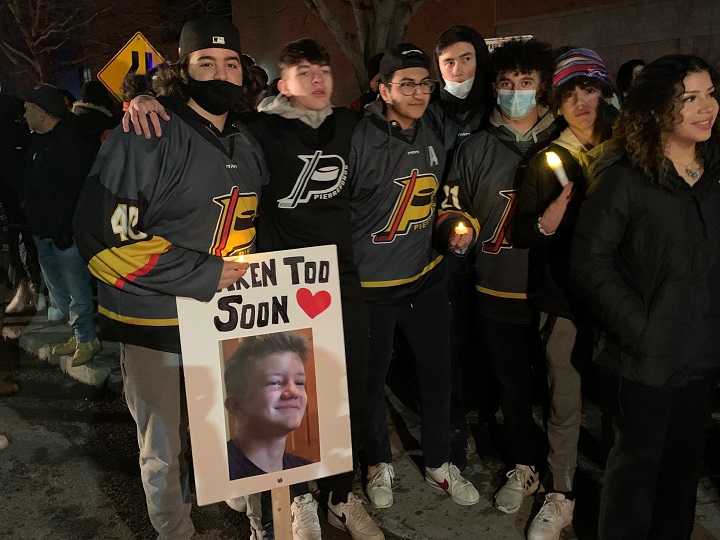 Friends and hockey mates of the late Lucas Gaudet hold a sign with his photo and the words "taken to soon." Thursday, March 10, 2022.