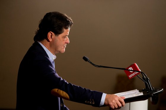 Unifor president Jerry Dias stands at a podium looking off to the right of theframe.