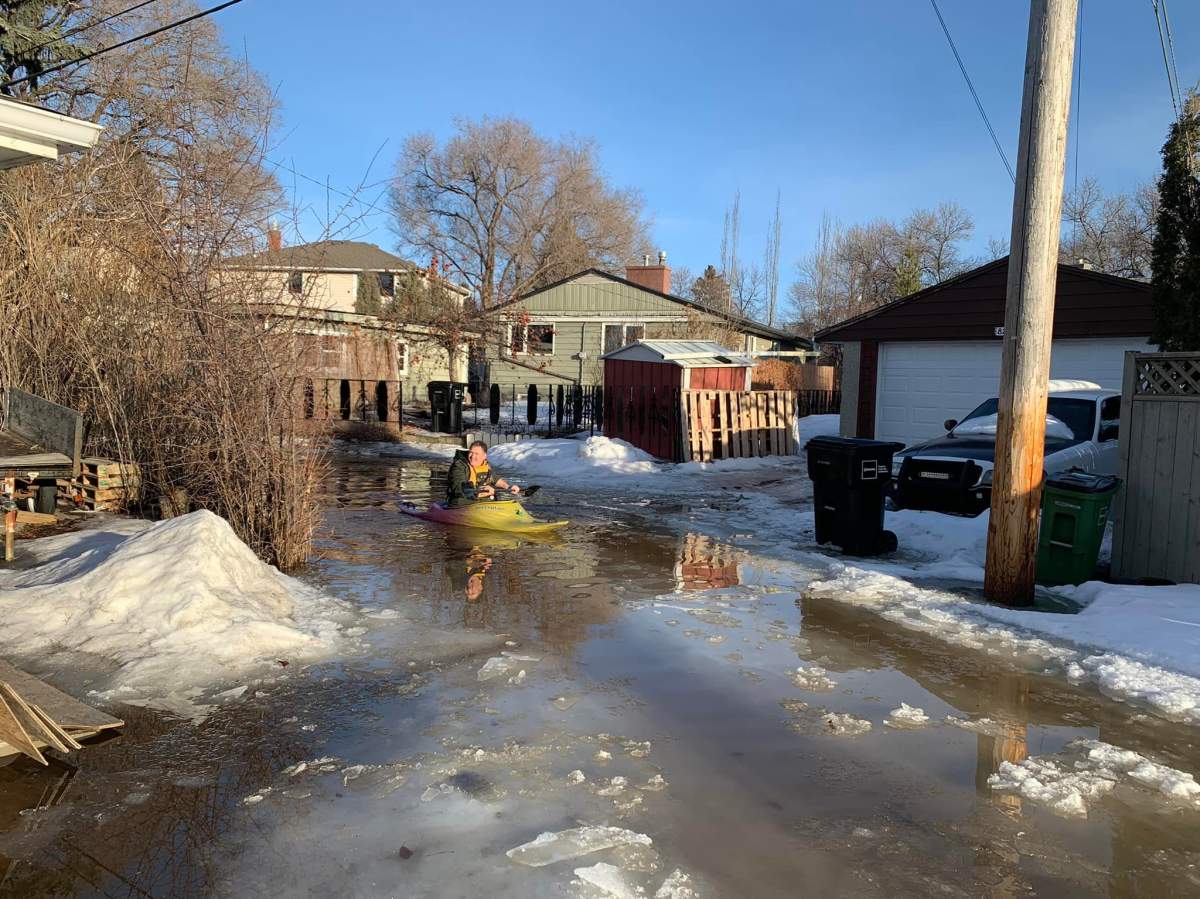 Chris Daubercies paddles down his alleyway in a kayak as large chunks of ice and spring melt have created a mess on March 18, 2022