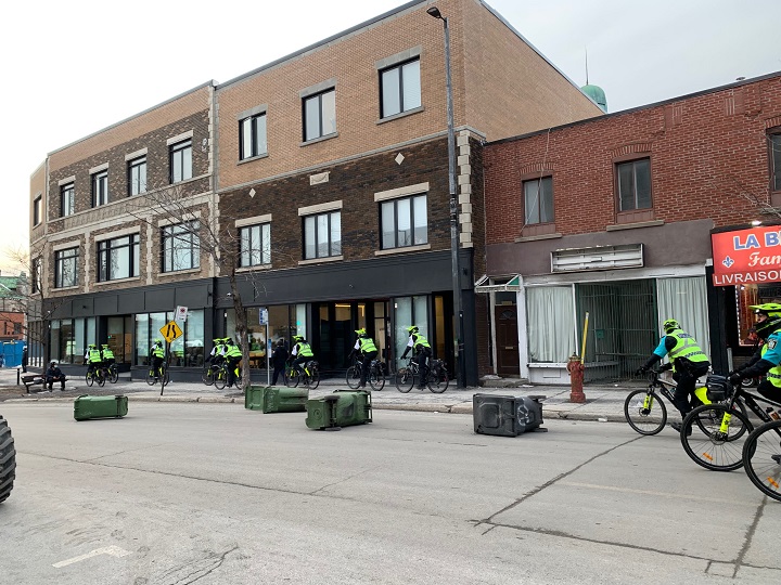 Officers navigate around garbage bins placed in the street during the annual anti-police brutality march on Tuesday, March 15, 2022.