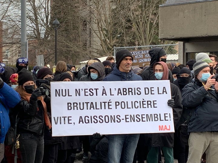A protester holds up a sign saying no one is shielded from police brutality during annual protest in Montreal. Tuesday, March 15, 2022.