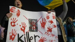 A women holds a white placard marked with bloody handprints and which calls Putin a "killer" at a pro-Ukraine rally.