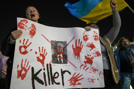 A women holds a white placard marked with bloody handprints and which calls Putin a "killer" at a pro-Ukraine rally.