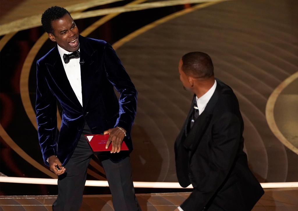 Presenter Chris Rock, left, reacts after being hit on stage by Will Smith while presenting the award for best documentary feature at the Oscars on Sunday, March 27, 2022, at the Dolby Theatre in Los Angeles.
