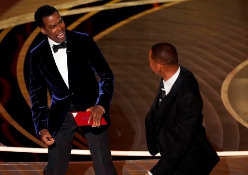 Presenter Chris Rock, left, reacts after being hit on stage by Will Smith while presenting the award for best documentary feature at the Oscars on Sunday, March 27, 2022, at the Dolby Theatre in Los Angeles.
