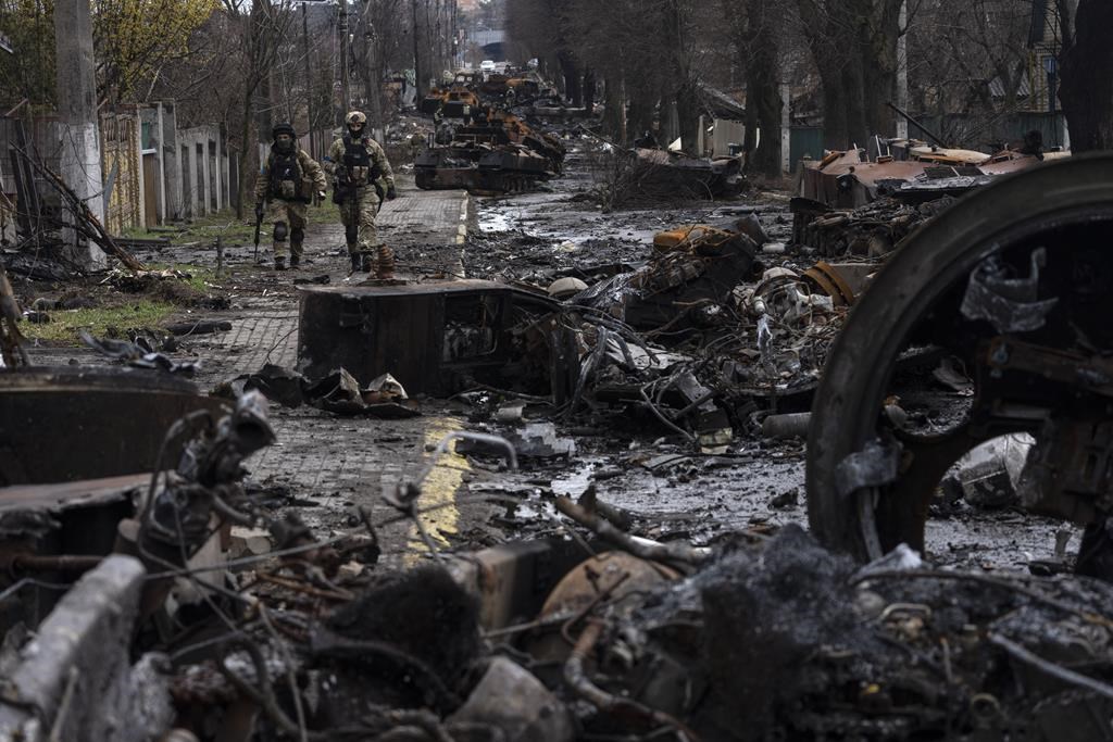 Soldiers walk amid destroyed Russian tanks in Bucha, on the outskirts of Kyiv, Ukraine, on April 3, 2022. (AP Photo/Rodrigo Abd)