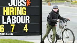 A woman checks out a jobs advertisement sign in Toronto on Wednesday, April 29, 2020.