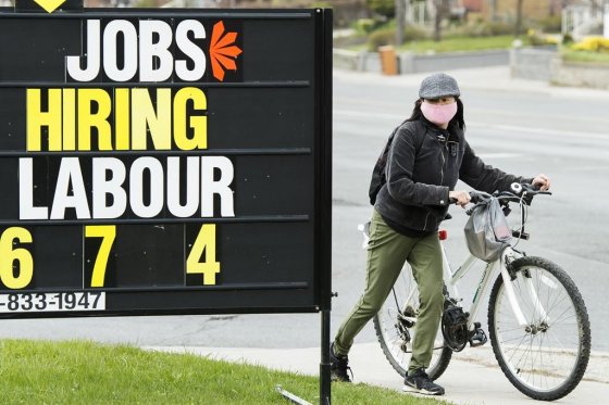 A woman checks out a jobs advertisement sign in Toronto on Wednesday, April 29, 2020.