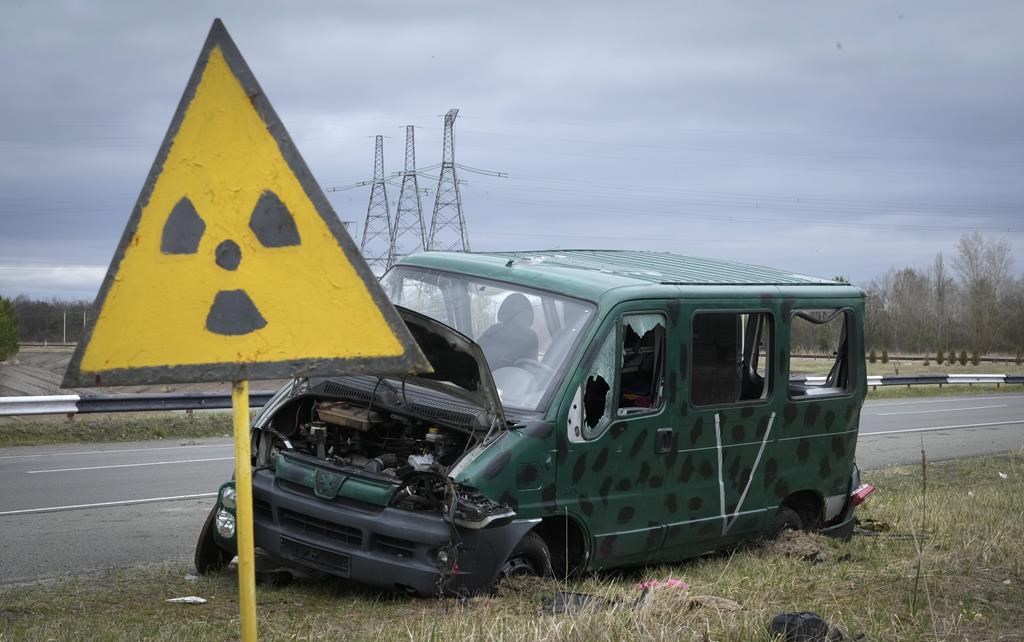 A radiation sign is seen near a broken Russian vehicle with a V letter, a sign of the Russian army, close to the Chornobyl nuclear power plant, Ukraine, Saturday, April 16, 2022. (AP Photo/Efrem Lukatsky).