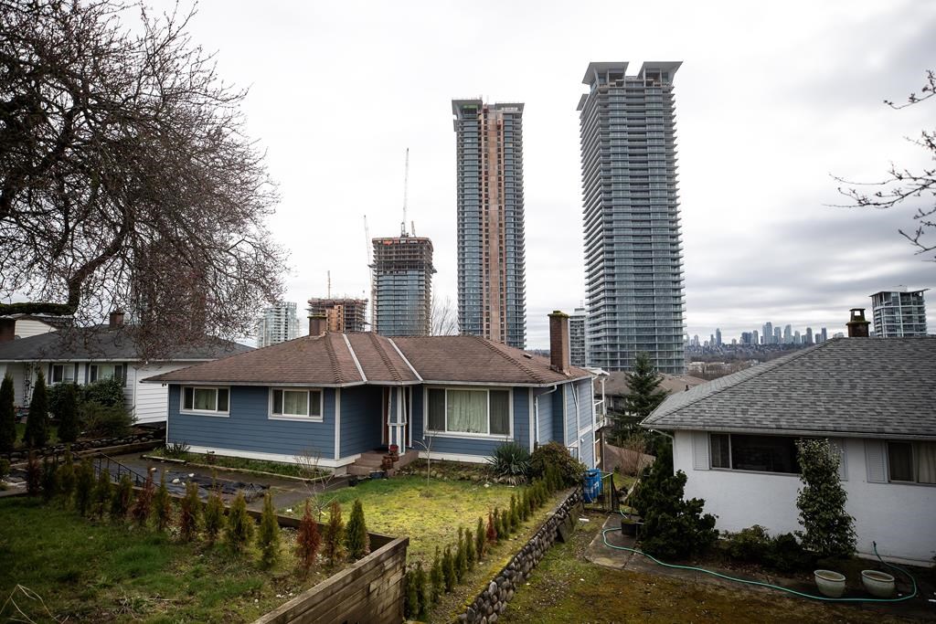 Condo towers under construction rise up a few blocks away from houses, in Burnaby, B.C., on Wednesday, March 2, 2022. 