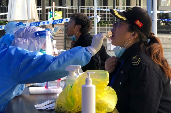 A medical worker collects sample swab sample from residents in a lockdown area in the Jingan district of western Shanghai.
