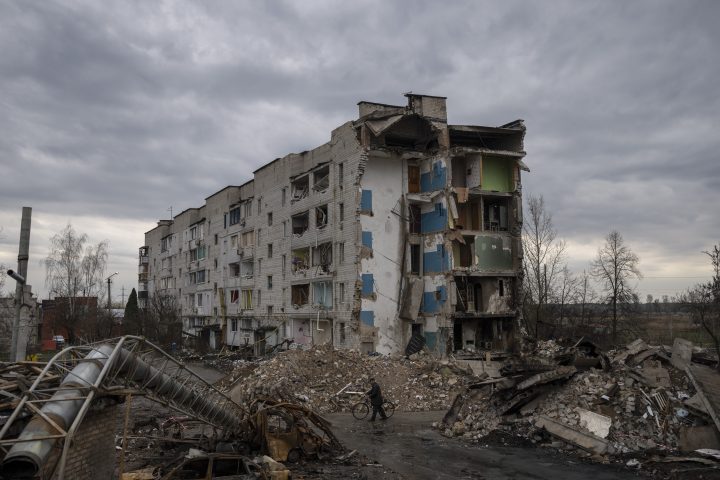 A man with a bicycle walks in front of a destroyed apartment building in the town of Borodyanka, Ukraine, on Saturday, April 9, 2022. Russian troops occupied the town of Borodyanka for weeks. Several apartment buildings were destroyed during fighting between the Russian troops and the Ukrainian forces in the town around 40 miles northwest of Kiev.