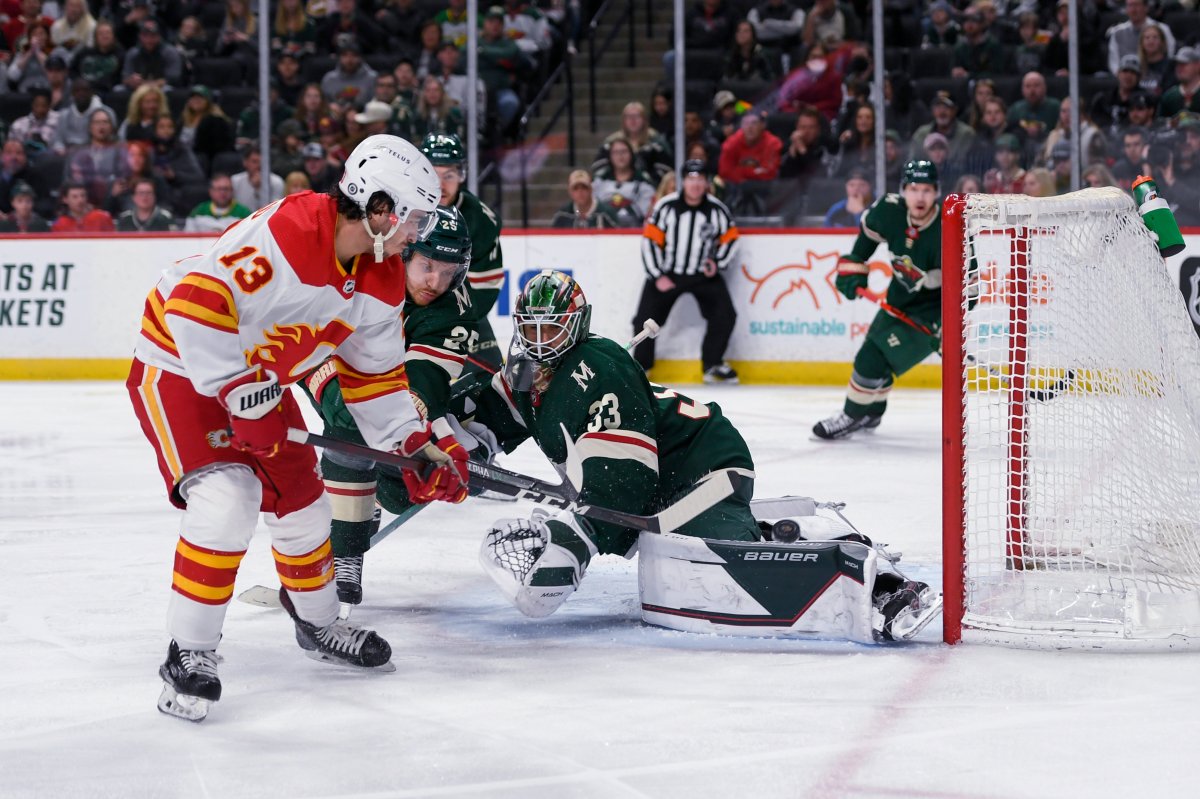 Calgary Flames left wing Johnny Gaudreau (13) flips the puck over Minnesota Wild goalie Cam Talbot (33) to score a goal during the second period of an NHL hockey game Thursday, April 28, 2022, in St. Paul, Minn.
