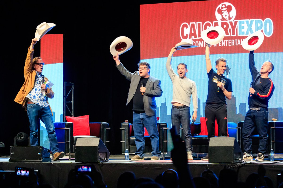 Fraser Abbott, Director of Business Development, Calgary Champions Program, Meetings & Conventions appointing (L-R) Sean Astin, Elijah Wood, Dominic Monaghan, and Billy Boyd with White Hats at the 2022 Calgary Expo.
