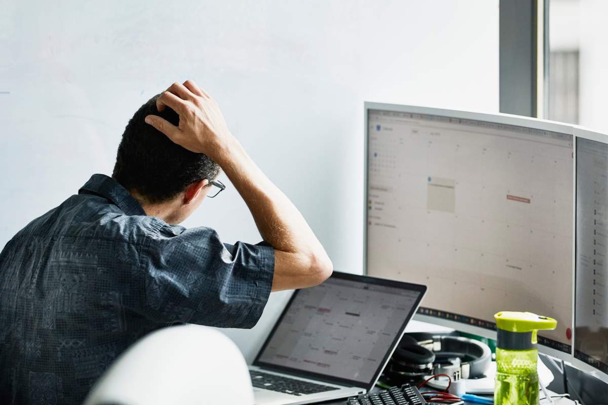 Engineer scratching head while looking at calendar on computer monitor in virtual reality lab