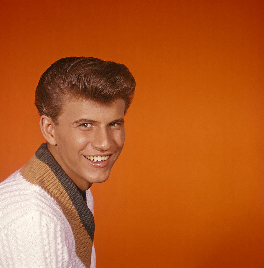 Pop singer Bobby Rydell photographed in front of an orange background.