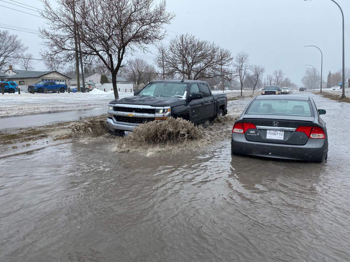 A truck drives past a flooded car in Elmwood – East Kildonan on Sunday, April 24, 2022.