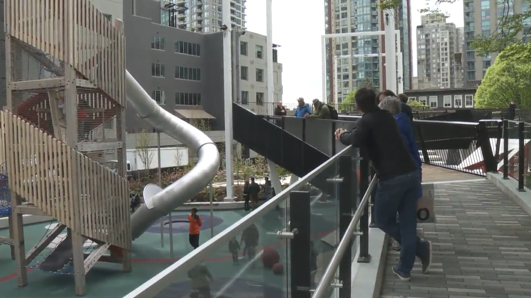 People enjoy the view from an elevated walkway as children play on new playground equipment at the first park to open in downtown Vancouver in over a decade on Friday. 