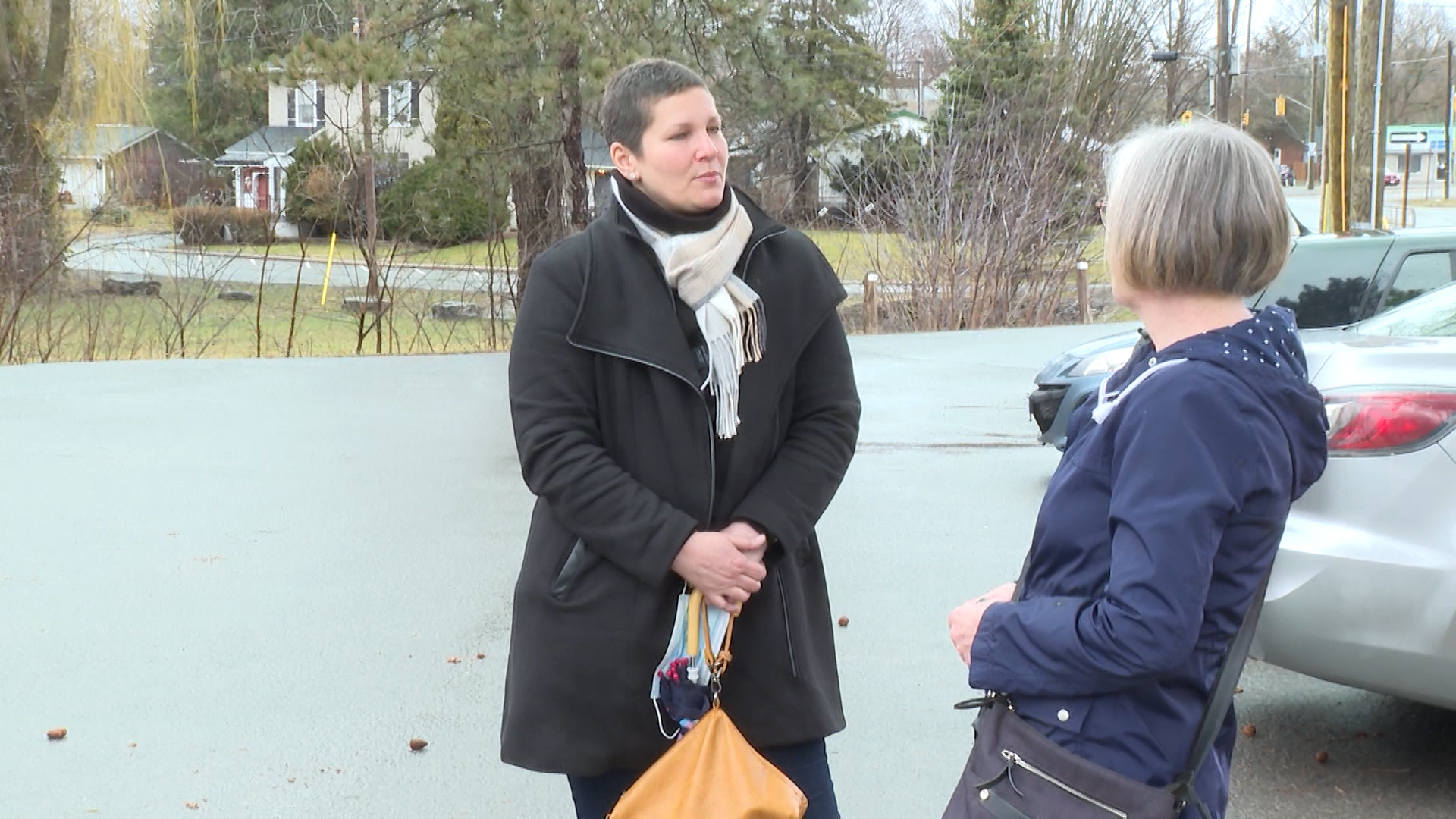 Two women conversing in a parking lot.