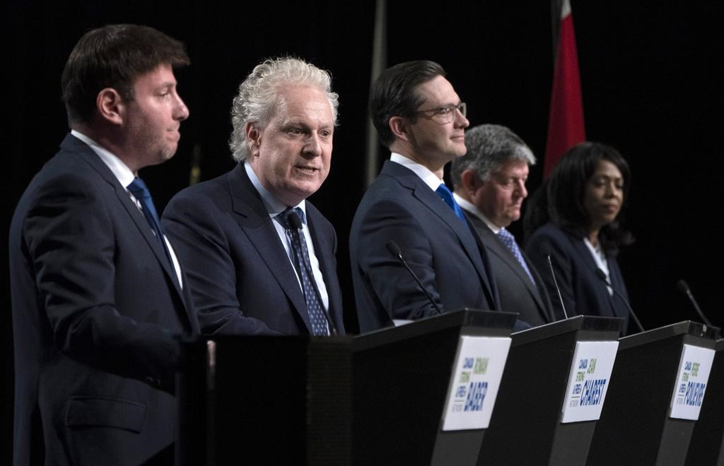 Conservative leadership candidates Roman Baber, left, Pierre Poilievre, Scott Aitchison and Leslyn Lewis listen to Jean Charest, second from left, speak during a debate at the Canada Strong and Free Network conference, in Ottawa, Thursday, May 5, 2022. 