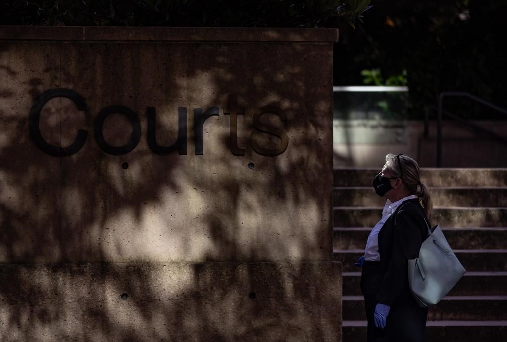 A person waits to enter B.C. Supreme Court, in Vancouver, B.C., Friday, Aug. 28, 2020. A British Columbia Supreme Court judge has found a man suffering from a mental disorder is not criminally responsible for the axe slaying of his mother. THE CANADIAN PRESS/Darryl Dyck.