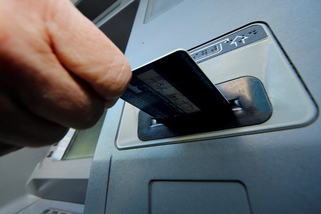 A person inserts a debit card into an ATM.