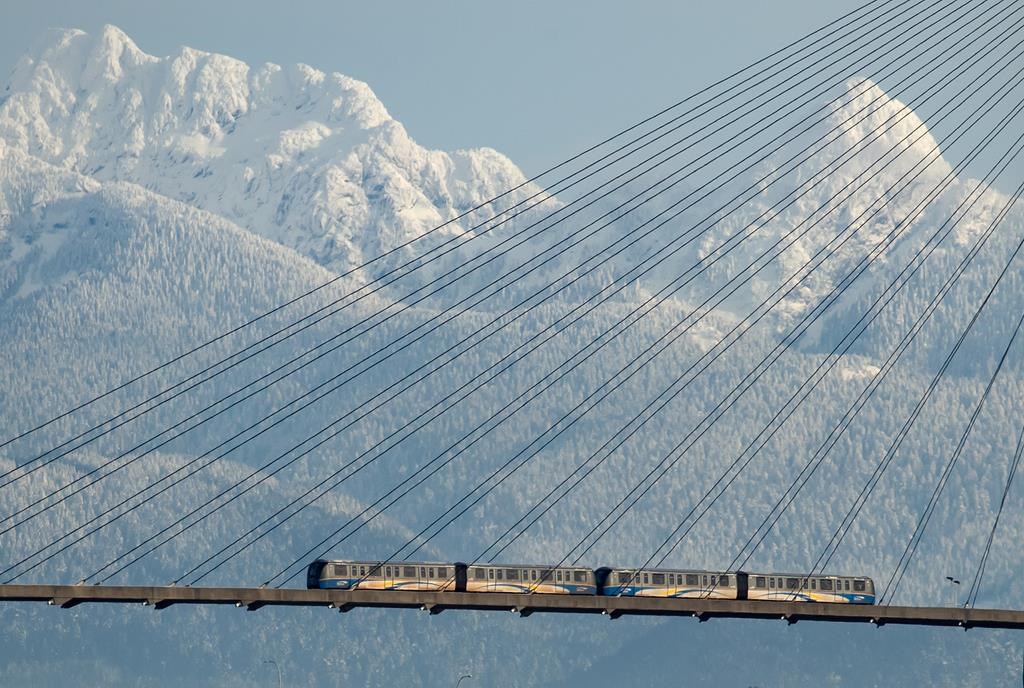 A Skytrain crosses over the Fraser River past snow-capped mountains in the distance, in New Westminster, B.C., on Tuesday, December 28, 2021.