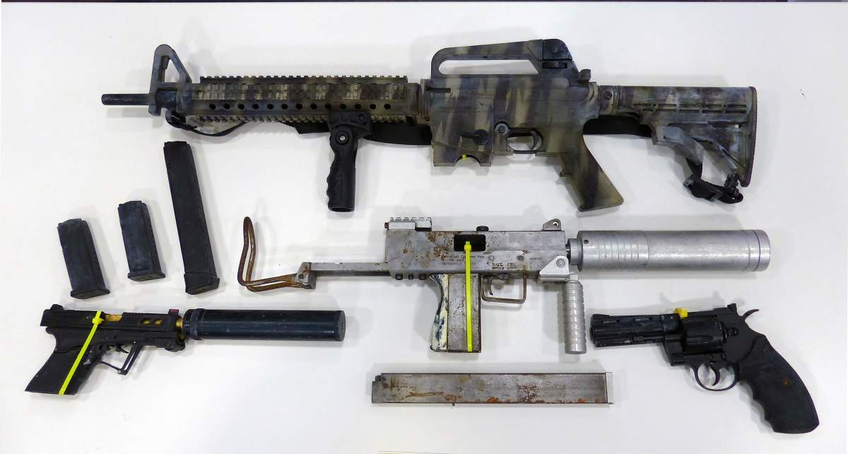 Three seized guns are laid out on a table