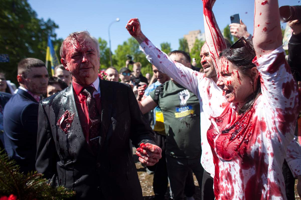 Activists shout slogans as Russian Ambassador to Poland, Ambassador Sergey Andreev, left, is covered with red paint in Warsaw, Poland, Monday, May 9, 2022.