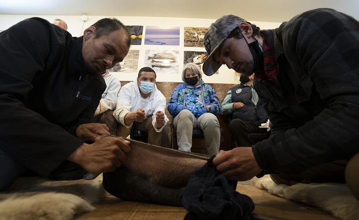 Governor General Mary Simon looks on as Ray Berthe Palliser(right) and Willia Ningeok make rope out of seal skin for the dog teams at the Unaaq Men’s Association Thursday, May 12, 2022 in Inukjuak, Quebec.  