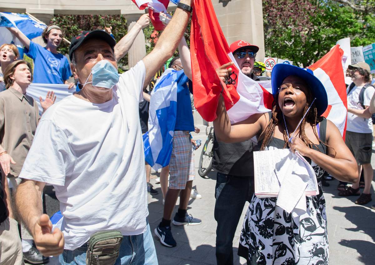 An anti Bill 96 protesters hold up a Canadian flag as a Bill 96 supporter shouts during a demonstration in Montreal, Saturday, May 14, 2022. THE CANADIAN PRESS/Graham Hughes