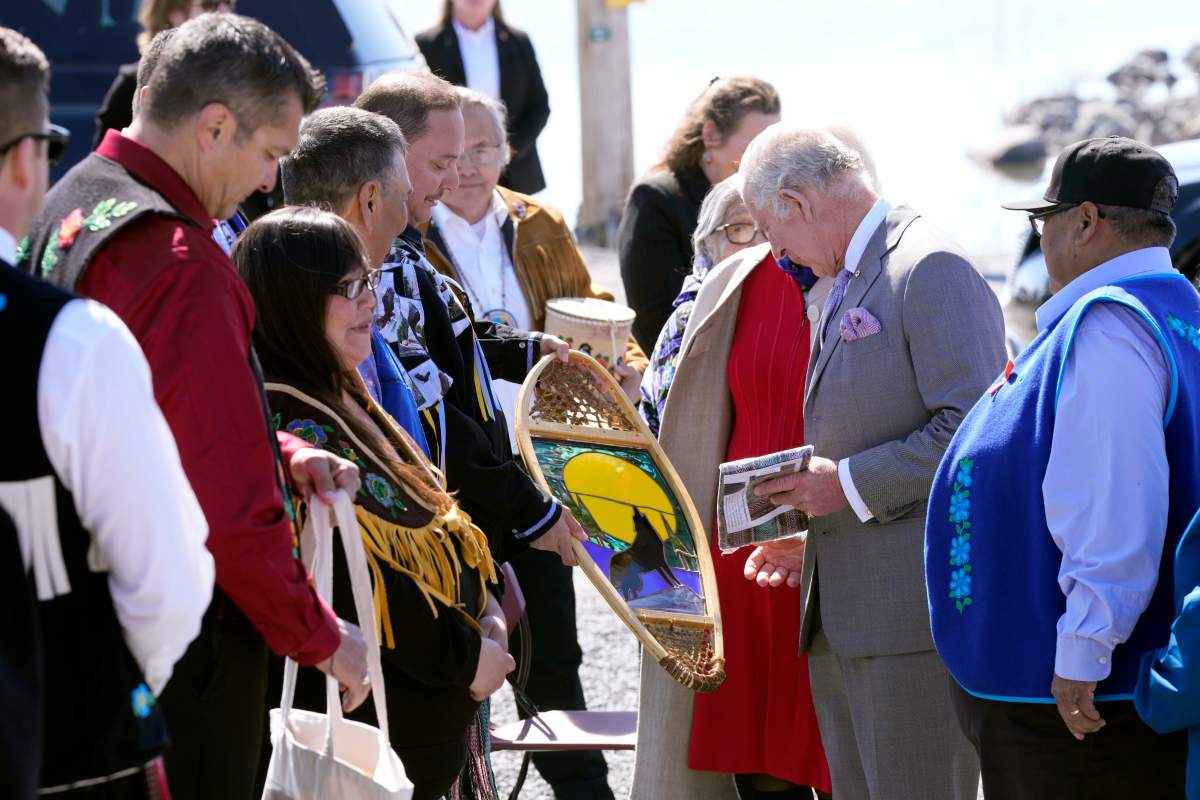 Prince Charles, second from right, and Camilla, Duchess of Cornwall, obscured behind him, receive a welcome gift after arriving in Yellowknife, Northwest Territories, during part of the Royal Tour of Canada, Thursday, May 19, 2022.