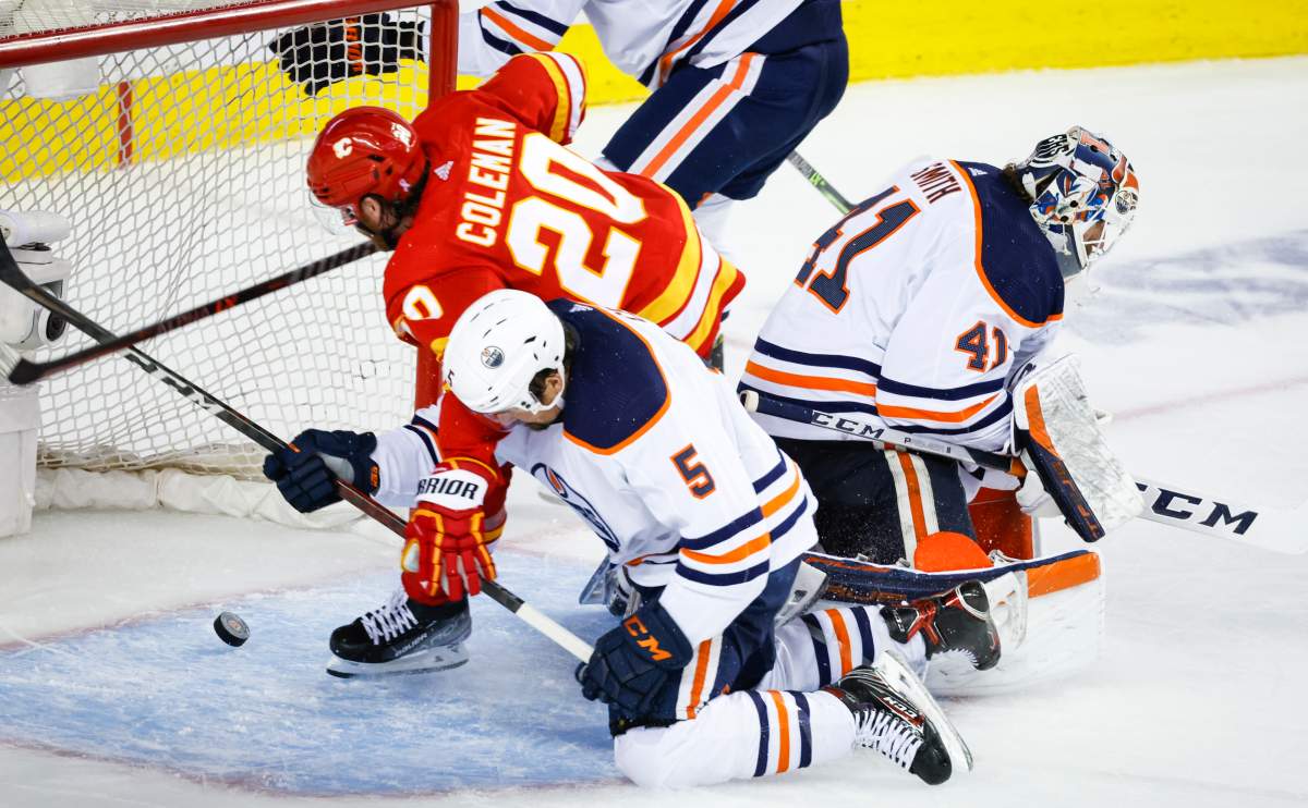 Edmonton Oilers, centre checks Calgary Flames forward Blake Coleman, left, as he scores a goal that was called back, while goalie Mike Smith loses track of the puck during third period NHL second-round playoff hockey action in Calgary, Thursday, May 26, 2022.