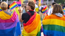 Wrapped in pride flags, a trio attends a Pride event in this stock image.