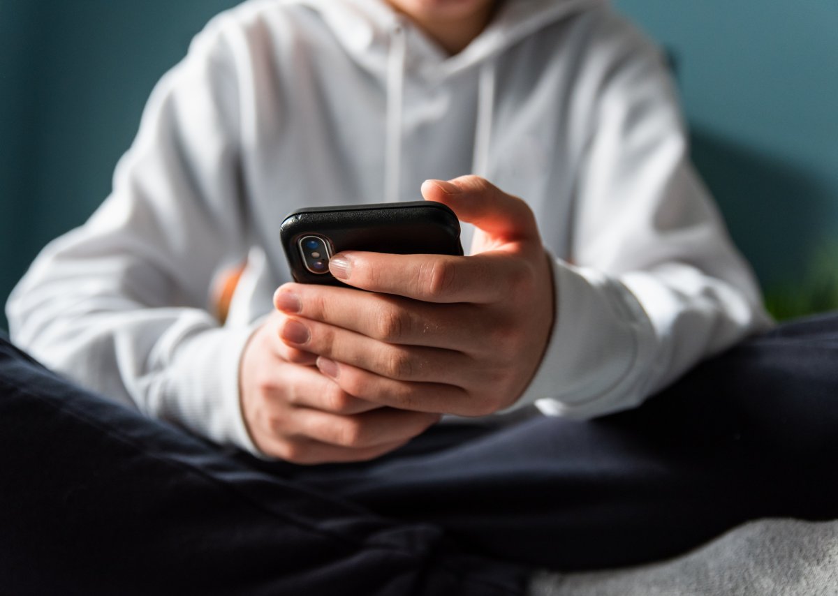A stock photo shows the hands of child sending text messages from a phone.